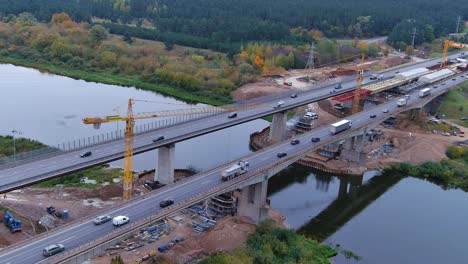 Construction-site-of-new-bridge-over-Neris-river-in-Lithuania,-aerial-drone-orbit-view