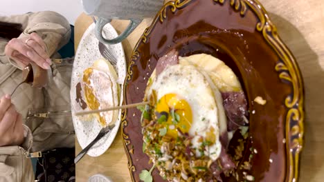 Female-hand-pouring-chocolate-over-pancakes-in-a-restaurant