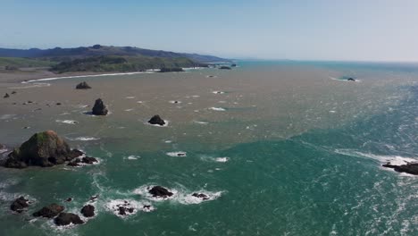 Drone-aerial-view-of-inland-river-water-interacting-with-the-pacific-ocean