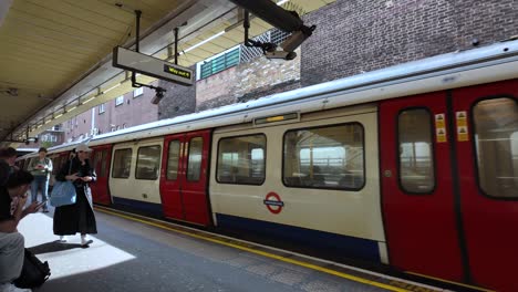 Un-Tren-De-La-Línea-Metropolitana-Llega-A-La-Estación-De-Metro-De-Finchley-Road-En-Londres,-Destacando-La-Eficiencia-Y-Conectividad-De-Los-Sistemas-De-Transporte-Urbano.