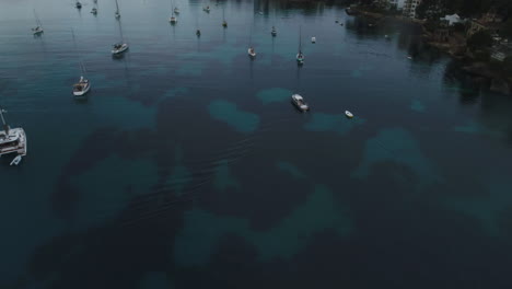 Aerial-Drone-Shot-of-an-Island-in-Spain-with-a-lot-of-Boats,-flying-backwards-and-tilting-up,-4k-UHD