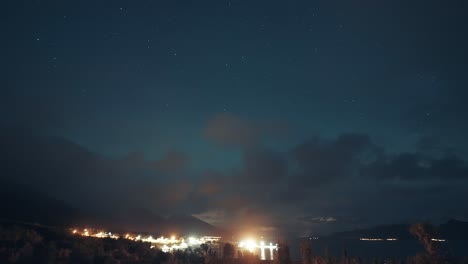 Night-skies-lit-by-the-northern-lights-above-the-brightly-illuminated-port-and-the-dark-fjord