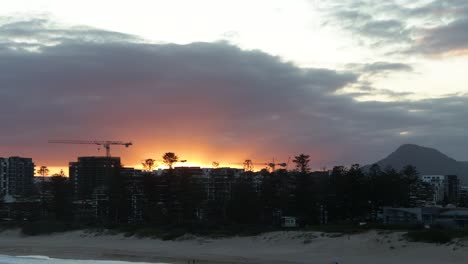 Orange-sunset-behind-city-skyline-silhouette-and-beach-Timelapse
