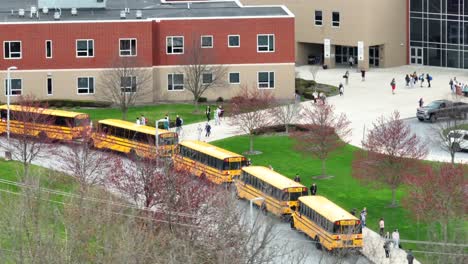 Schüler-Und-Studenten-Verlassen-Die-Schule-Und-Steigen-Auf-Dem-Parkplatz-In-Den-USA-In-Gelbe-Schulbusse-Ein