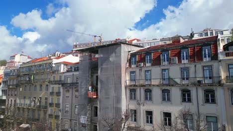 Vista-Aérea-De-La-Ciudad-De-Lisboa-Con-Un-Edificio-En-Construcción-Con-Trabajadores-Descendiendo-Sobre-Una-Plataforma-Elevadora,-Lisboa,-Portugal