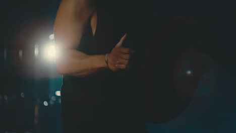 Close-up-of-male-doing-bicep-curls-with-45-pound-plate-in-dark-gym,-backlit-in-4k-800fps