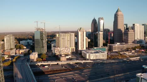 Aerial-of-Atlanta-Midtown-freeway-moving-traffic,-real-estate-construction-and-development,-skyline-buildings,-luxury-condominiums-at-sunset