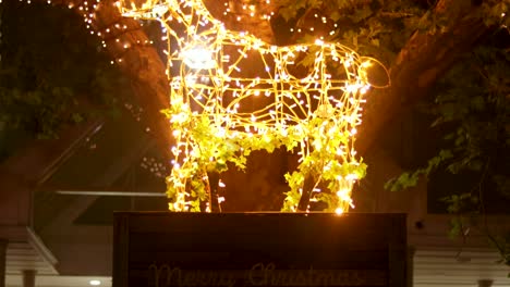 light-up-White-Reindeer-on-merry-christmas-podium-with-lit-tree-in-background