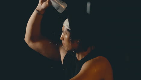 Asian-male-athlete-squirting-water-on-head-after-hot-sweaty-workout,-extreme-slow-motion-medium-static-shot-at-4k-800fps