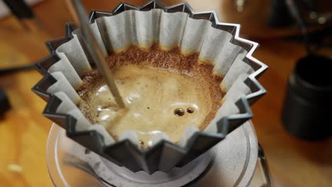 über-Den-Kaffeefilter-Gießen-Und-Mit-Einem-Metallzahnstocher-Umrühren