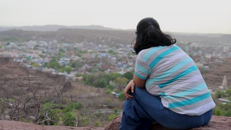 isolate-girl-watching-city-landscape-at-mountain-top-with-dramatic-sky-at-dusk-video-is-taken-at-mehrangarh-jodhpur-rajasthan-india