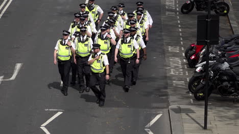 A-unit-of-Metropolitan-police-officers-check-their-radio-communications-as-they-march-along-a-road-during-a-public-order-event