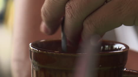 Man-stirring-his-cup-of-coffee-on-a-busy-coffee-shop-in-Cadiz-City,-Negros-Occidental,-Philippines