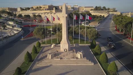 Maltese-flags-waving-in-the-wind-at-the-Malta-War-Memorial-in-Valletta,-Malta---drone-aerial-shot