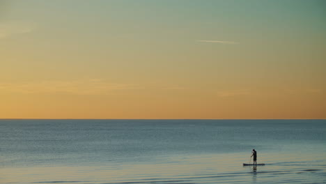 Person-Stand-Up-Paddleboarding-Bei-Sonnenuntergang-Auf-Ruhigem-Meer,-Sommer-Hintergrund