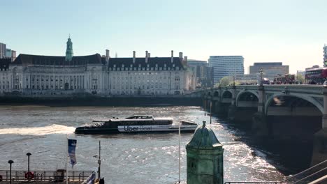 Sonnenbeschienene-Szene-Eines-Uber-Bootes,-Das-Unter-Der-Westminster-Bridge-In-London-Hindurchfährt