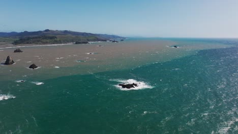 High-elevation-drone-shot-flying-over-the-ocean-and-inland-fresh-water-mixing