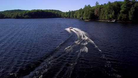 Girl-Water-Skiing-on-Blue-Lake,-Wide-Aerial-Drone-Tracking-Shot