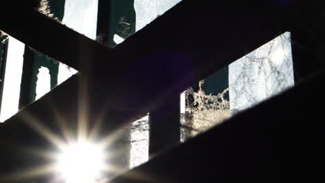 Alcatraz-Bundesgefängnis-Detail,-Sonnenstrahlen-Auf-Metallstangen-Und-Spinnweben-Auf-Fenster-Im-Zellengebäude