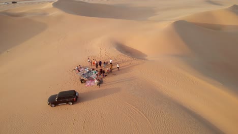 Aerial-view-of-friends-having-bbq-in-the-desert-of-Abu-Dhabi,-United-Arab-Emirates