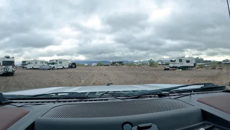POV-driving-on-gravel-trail-through-groups-of-dispersed-campers-in-the-Sonoran-desert-on-a-cloudy-winter-day-in-southern-Arizona
