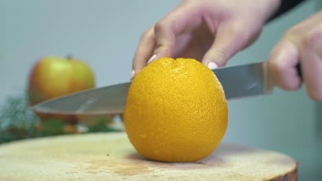 SLOW-MOTION-cutting-big-orange-citrus-fruit-in-two-parts-with-a-knife