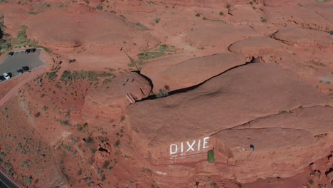 Drone-flies-over-road-and-looks-up-at-red-rock-formations-and-desert-mountains