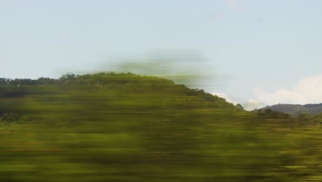 speeding-past-beautiful-mountains,-lakes-and-trees-on-warm-day