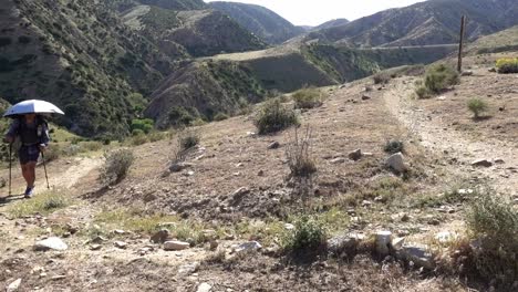 Man-hiking-the-Pacific-Crest-Trail-in-southern-California-desert-using-a-chrome-umbrella