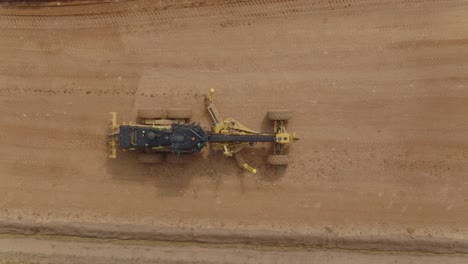 Top-down-of-a-grader-heavy-machinery-flattening-out-construction-site-ground