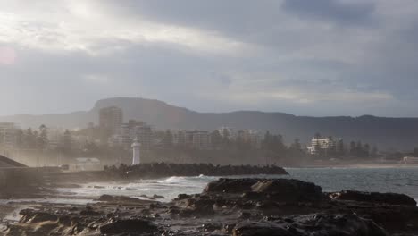 Water-crashing-into-rocky-shore-of-lighthouse-and-city-of-Wollongong-NSW