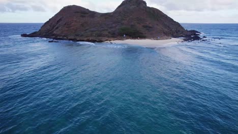 drone-footage-of-an-islet-off-the-coast-of-Oahu-showing-the-wave-refraction-as-the-ocean-water-changes-course-around-the-island