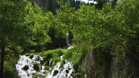 Aerial-dolly-shot-of-the-upper-Roughlock-Falls-showcasing-the-rushing-water-in-Spearfish-Canyon,-South-Dakota-behind-beautiful-green-summer-leaves