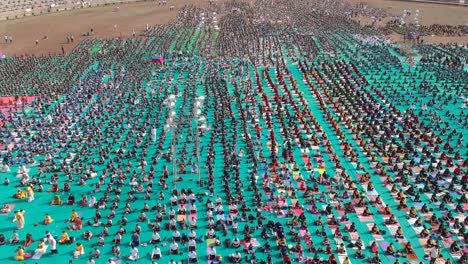 Aerial-footage-of-people-performing-Yoga-in-a-stadium-at-Ahmednagar,-India-on-the-occasion-of-International-Yoga-Day-along-with-school-students