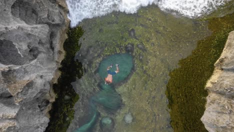 Vista-Aérea-Superior-Del-Hombre-Nadando-En-La-Piscina-Natural-De-Angel&#39;s-Billabong,-Boom-Up,-Bali