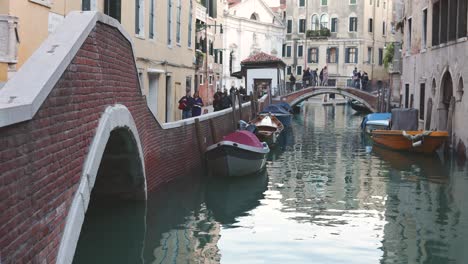 People-walk-along-canals-sidewalk-and-bridges-in-Venice-old-town