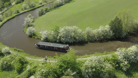 Eine-Luftaufnahme-Eines-Kanalboots,-Das-An-Einem-Sonnigen-Frühlingstag-Durch-Eine-Kanalecke-Navigiert,-Umgeben-Von-Der-Landschaft-Yorkshires