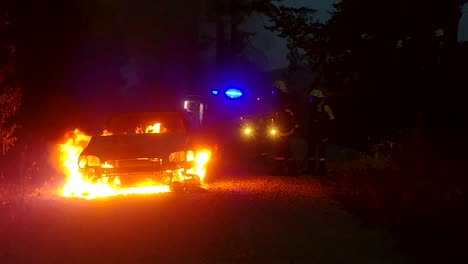 Zwei-Freiwillige-Feuerwehrleute-Löschen-Nachts-Ein-Brennendes-Auto