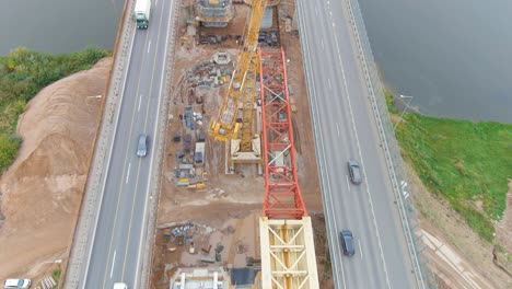Busy-highway-road-and-construction-site-for-new-bridge-over-Neris-river,-aerial-drone-view