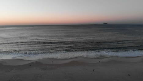Aerial-early-morning-sunrise-over-an-almost-empty-Copacabana-beach-with-calm-ocean-waves-coming-in