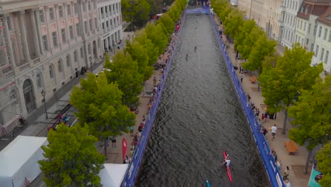 Aerial-shot-of-people-kayaking-through-canal-in-city-centre
