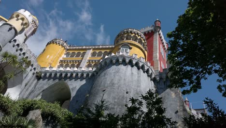 Staring-up-at-the-colorful-Pena-Palace-in-Sintra,-Portugal,-pan-left