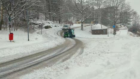 Heavy-Snowfall-and-Small-Green-Snow-Plow-and-White-Van-Passing-By