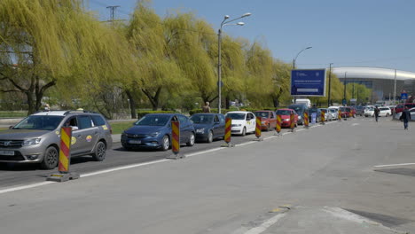 Statische-Weitwinkelaufnahme-Einer-Großen-Autoschlange,-In-Der-Menschen-Geduldig-Darauf-Warten,-Im-Zweiten-Drive-Through-Impfzentrum-Für-Covid-19-In-Rumänien-An-Der-Reihe-Zu-Sein-Und-Den-Pfizer-Biontech-Impfstoff-Zu-Erhalten