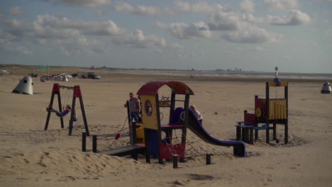 Kinder-Spielen-Auf-Schaukeln-Und-Rutschen-Am-Strand