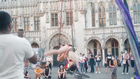 Female-street-performer-giving-acrobatic-performance-on-the-Grand-Place-of-Brussels-in-front-of-crowd-on-warm-summer-evening