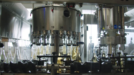 Amazing-wide-in-slow-motion-shot-of-machinery-that-fills-white-wine-bottles-inside-a-wine-factory-in-Burgos,-Spain