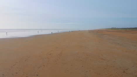 Expansive-sandy-beach-in-Saint-Jean-de-Monts,-France-with-distant-figures-and-gentle-waves