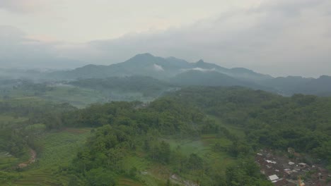 Silhouette-of-mountain-and-forest-on-foggy-Indonesia-day,-aerial-view