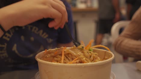 Person-eating-hot-noodles-in-a-market